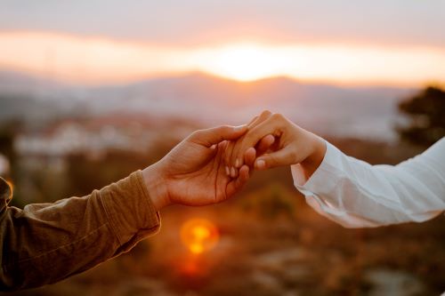 Romantic getaways, holding hands with sunset behind